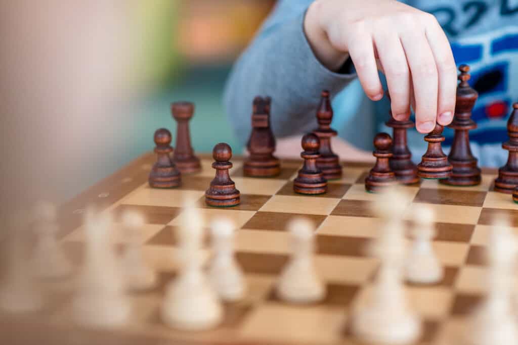 Beginner chess player holding his hand over black chess pieces